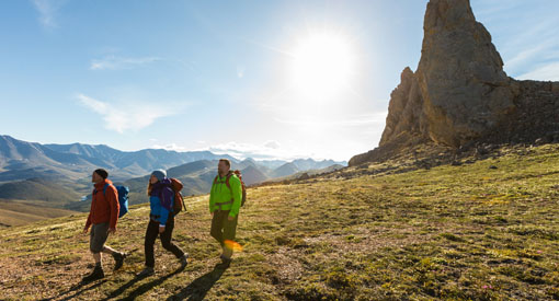 Hikers with the sun and mountains in the background.