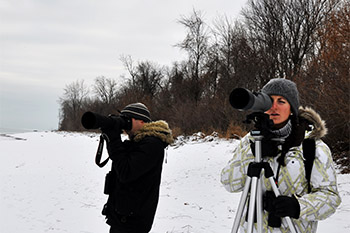 Two people using long-focus lens cameras in the winter.