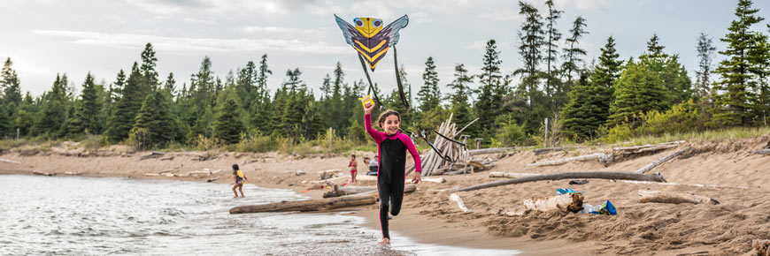 A young girl is flying a kite on Horseshoe Beach.
