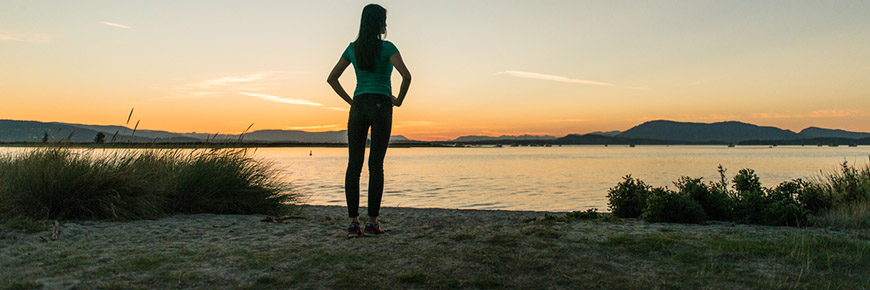 A woman on a sandy beach at sunset at Sidney Spit