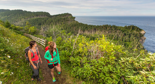 Two women hiking on the edge of cliffs to the Land’s End at the far end of Les Graves trail.