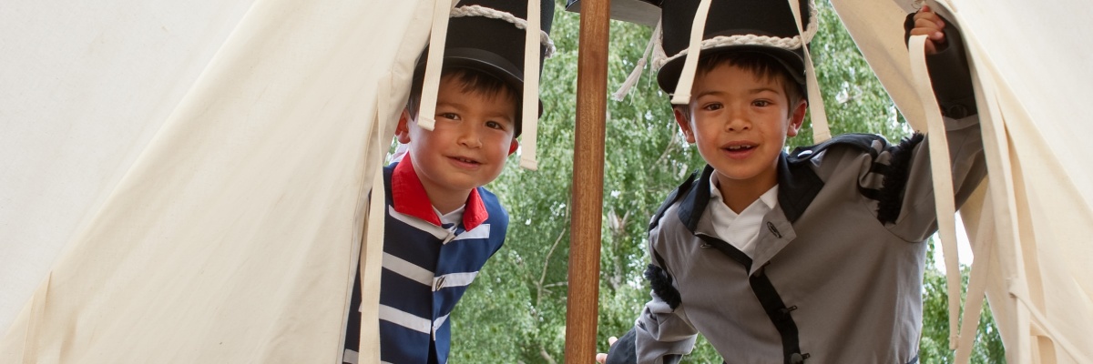 Child visitors in period costume in a tent from the re-enactment of the War of 1812.