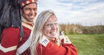A young woman looks back as she prepares to shoot a Snider-Enfield rifle with a costumed 78th Highlander during the Ready, Aim, Fire program at Halifax Citadel National Historic Site. 
