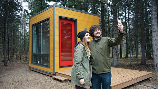 Two young adults taking a selfie in front of a MicrOcube at Riding Mountain National Park.