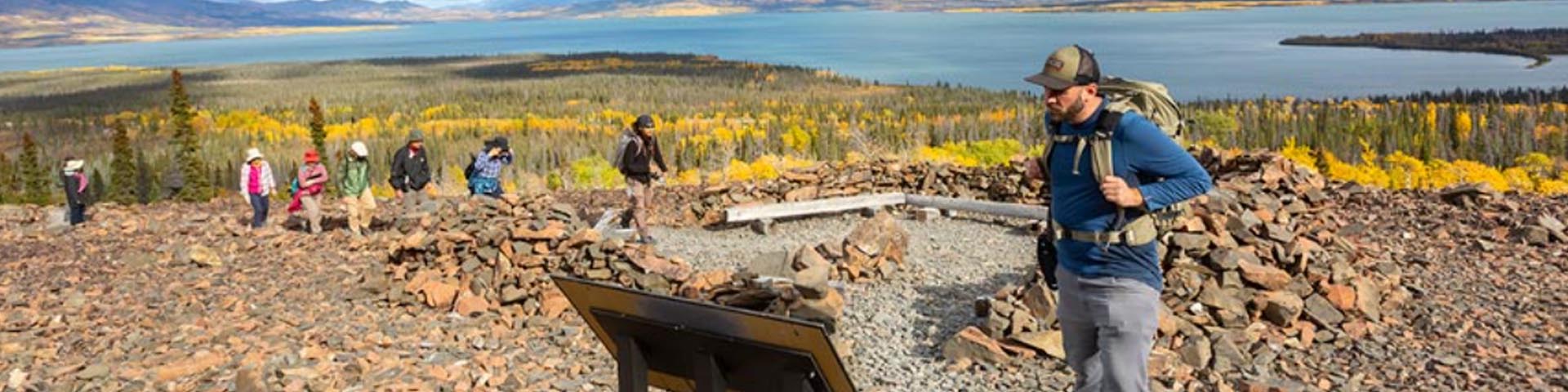 Visitors hiking on Rock Glacier Trail with Dezadeash Lake in the background at Kluane National Park and Reserve.