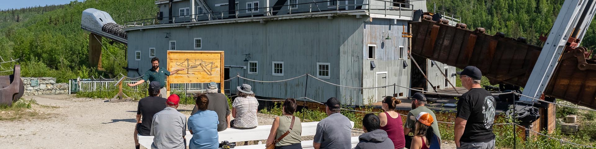 A guide with visitors in front of the dredge at Dredge No. 4 National Historic Site.