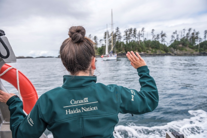 A Parks Canada employee waves from aboard a boat to someone passing.